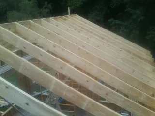 New roof rafters set over an addition before sheathing in Felton