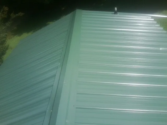 New green metal panels meeting at the ridge of a roof — Flat Roof Repair work by our crew in Felton